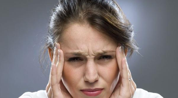 Mujer sujetándose las sienes con gesto de dolor de cabeza